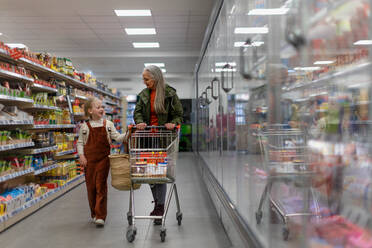 Eine Großmutter kauft mit ihrer Enkelin Lebensmittel im Supermarkt. - HPIF04020