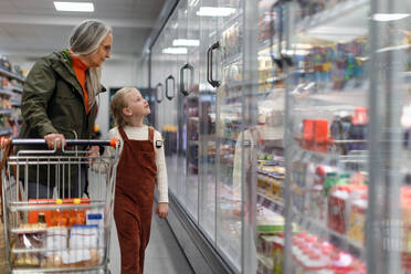 Eine Großmutter kauft mit ihrer Enkelin Lebensmittel im Supermarkt. - HPIF04021