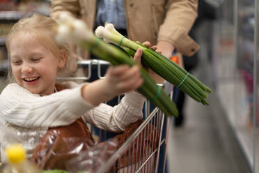 Ein kleines Mädchen sitzt im Einkaufswagen beim Familieneinkauf im Supermarkt - HPIF04025
