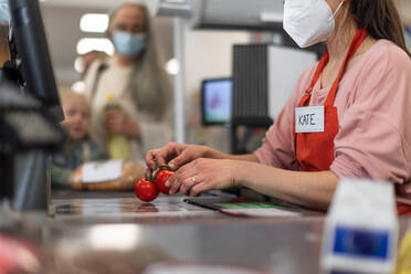 Checkout counter cashier scans vegetable in supermarket. - HPIF04035