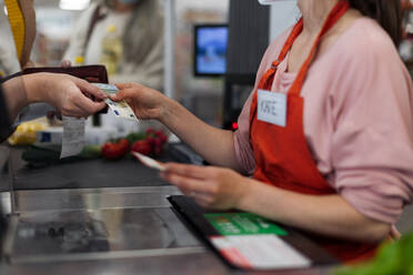 Aufnahme einer Frau, die einer Verkäuferin im Supermarkt Geld gibt - HPIF04037