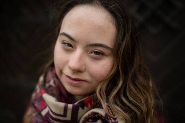 Nahaufnahme einer jungen Frau mit Down-Syndrom, die in die Kamera schaut, auf schwarzem Hintergrund - HPIF04075