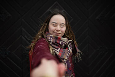 Eine junge Frau mit Down-Syndrom schaut in die Kamera auf schwarzem Hintergrund - HPIF04076