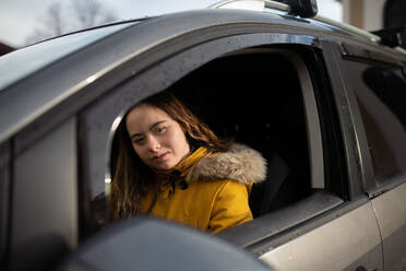 A young woman with Down syndrome driving a car and looking at camera. - HPIF04083