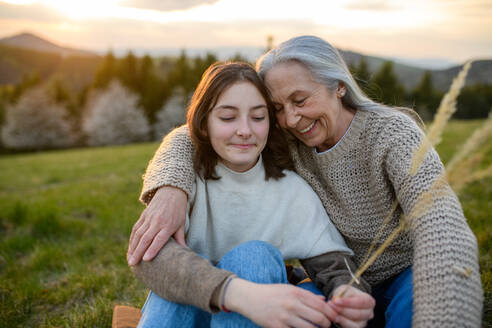 Eine glückliche ältere Großmutter mit Teenager-Enkelin umarmt in der Natur am Frühlingstag. - HPIF04130