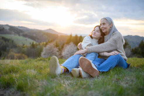 A happy senior grandmother with teenage granddaguhter hugging in nature on spring day. - HPIF04131