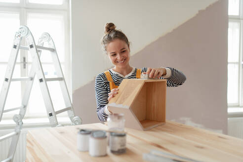 Portrait of young woman remaking shelf in her house. Concept of reusing materials and sustainable lifestyle. - HPIF04194