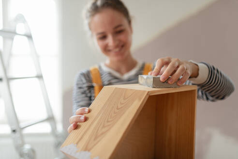 Portrait of young woman remaking shelf in her house. Concept of reusing materials and sustainable lifestyle. - HPIF04195