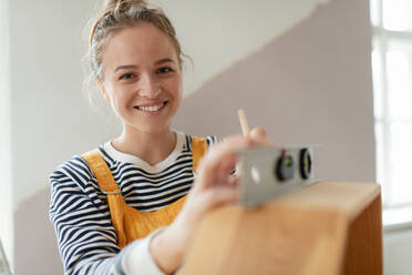 Portrait of young woman remaking shelf in her house. Concept of reusing materials and sustainable lifestyle. - HPIF04196