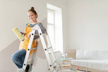Glückliche junge Frau, die ihr neues Haus renoviert und die Wände streicht. Konzept der Renovierung, unabhängige Frauen und nachhaltiger Lebensstil. - HPIF04201