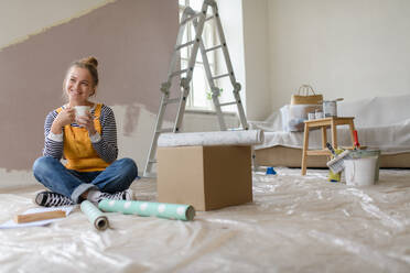 Happy young woman having break during renovation her house. Thinking about new projects. Concept of reusing materials and sustainable lifestyle. - HPIF04204