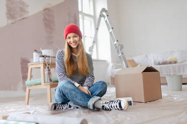 Glückliche junge Frau, die eine Pause beim Streichen von Wänden in ihrem Haus macht und über neue Projekte nachdenkt. Konzept der Wiederverwendung von Materialien und des nachhaltigen Lebensstils. - HPIF04207