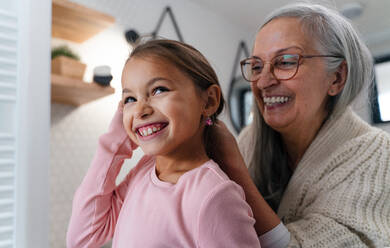 A senior grandmother and granddaughter standing indoors in bathroom, daily routine concept. - HPIF04217