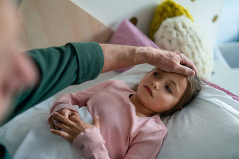Ein Großvater kümmert sich um seine kranke, im Bett liegende Enkelin. - HPIF04257