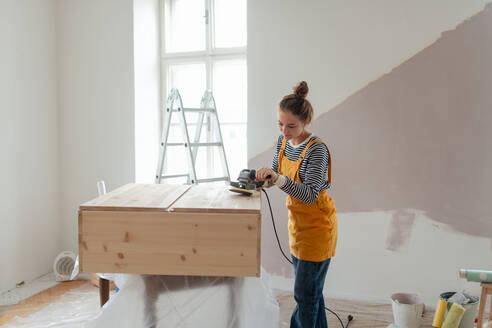Glückliche junge Frau, die einen Holzschrank in ihrem Haus umbaut. Konzept der Wiederverwendung von Materialien und des nachhaltigen Lebensstils. - HPIF04270