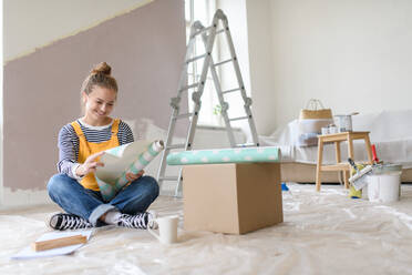 Glückliche junge Frau, die bei der Renovierung ihres Hauses eine Pause macht und über neue Projekte nachdenkt. Konzept der Wiederverwendung von Materialien und des nachhaltigen Lebensstils. - HPIF04278