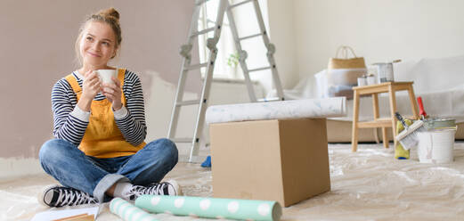 Glückliche junge Frau, die bei der Renovierung ihres Hauses eine Pause macht und über neue Projekte nachdenkt. Konzept der Wiederverwendung von Materialien und des nachhaltigen Lebensstils. - HPIF04279