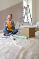 Happy young woman having break during renovation her house. Thinking about new projects. Concept of reusing materials and sustainable lifestyle. - HPIF04280