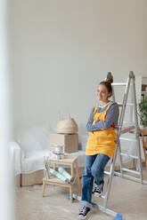 Glückliche junge Frau, die bei der Renovierung ihres Hauses eine Pause einlegt. - HPIF04282