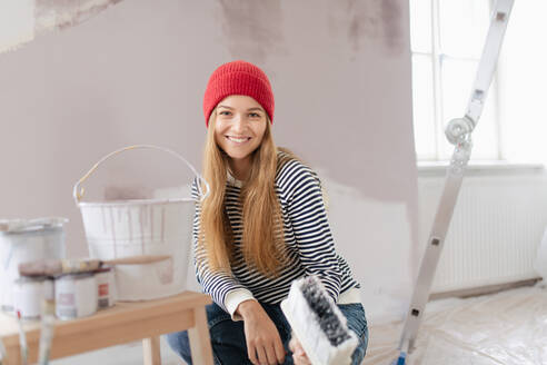 Glückliche junge Frau, die ihr neues Haus renoviert und die Wände streicht. Konzept der Renovierung, unabhängige Frauen und nachhaltiger Lebensstil. - HPIF04284