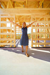 Excited senior woman inside of her unfinished ecological wooden house. - HPIF04293