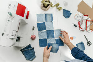 Hände eines Modedesigners bei der Arbeit an einem Stück Jeansstoff auf einem Tisch - YTF00344