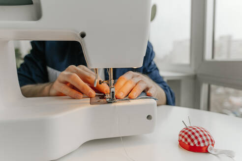 Hände eines Modedesigners nähen Stoff auf einer Maschine in einer Werkstatt - YTF00345