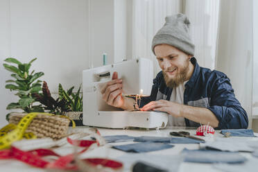 Smiling fashion designer working on sewing machine in workshop - YTF00347