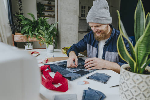 Happy fashion designer stitching pocket on shopping bag in workshop - YTF00355