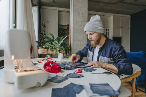 Modedesignerin mit Strickmütze bei der Arbeit an einer Denim-Tasche - YTF00356