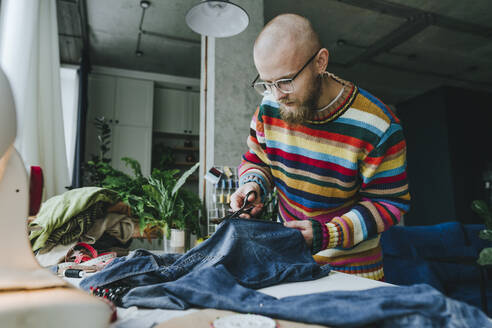 Modedesigner schneidet Denim-Stoff auf einem Tisch in einer Werkstatt zu - YTF00361