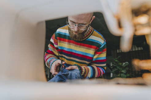 Modedesigner schneidet Denim-Stoff in der Werkstatt zu - YTF00362