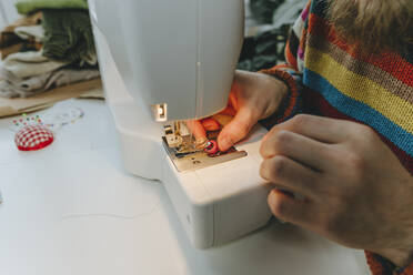 Hände einer Modedesignerin beim Einstellen des Fadens in der Nähmaschine - YTF00368