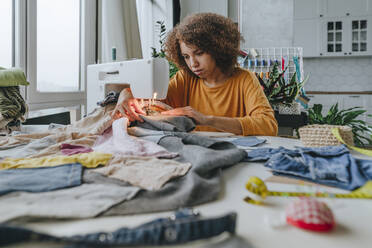 Junge Modedesignerin beim Nähen von Kleidung in einer Werkstatt - YTF00371
