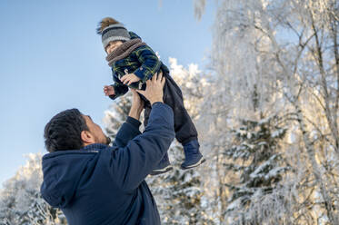Playful man carrying son in winter park - ANAF00658