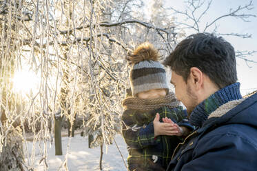 Glücklicher Mann hält seinen Sohn im Winterpark - ANAF00660