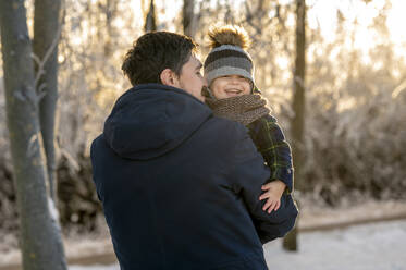 Lächelnder Mann mit glücklichem Sohn im Winterpark - ANAF00663