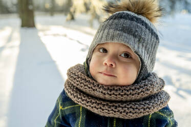 Cute boy wearing scarf and knit hat in winter park - ANAF00669