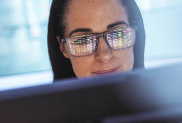 Händler, der den Aktienmarkt mit Hilfe eines Laptops mit Spiegelung auf der Brille analysiert - ABRF01038