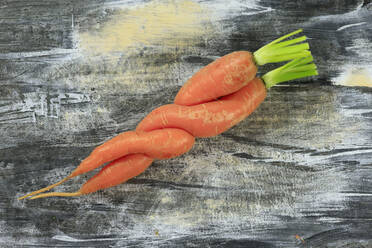 Two intertwined carrots lying on wooden surface - JTF02282