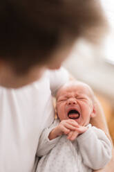 A father holding his crying newborn son at home. - HPIF04332