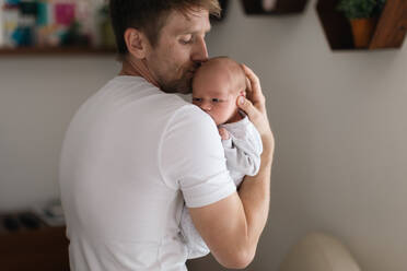 Ein Vater hält seinen neugeborenen Sohn zu Hause im Arm. - HPIF04333