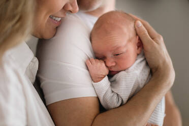 A smiling mother and father holding their newborn baby daughter at home - HPIF04336