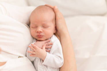 An unrecognizable mother holding her newborn son at home, close-up - HPIF04339