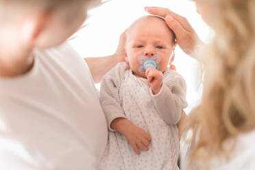 Nahaufnahme von Mutter und Vater, die ihr neugeborenes Kind zu Hause im Arm halten - HPIF04343