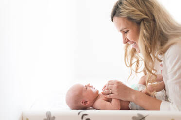 A happy mother bonding with her newborn son who is lying on changing mat at home. - HPIF04348