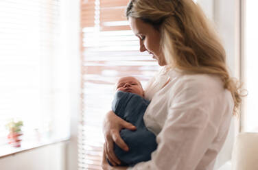 Eine junge Mutter hält ihren neugeborenen Sohn zu Hause im Arm. - HPIF04350