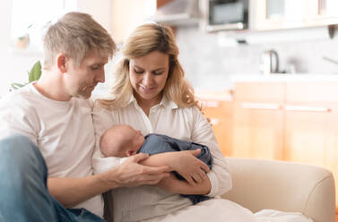 Eine lächelnde Mutter und ein Vater, die ihre neugeborene Tochter zu Hause im Arm halten - HPIF04351