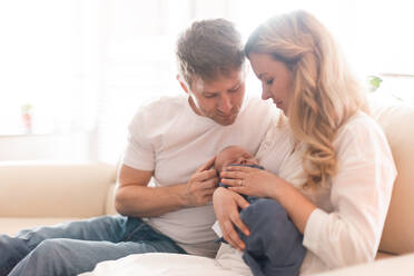 A smiling mother and father holding their newborn baby daughter at home - HPIF04352