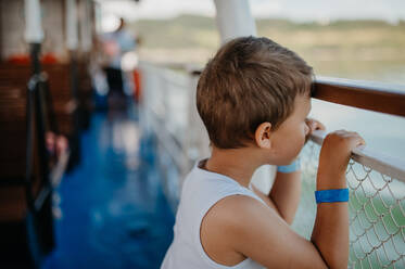 Ein kleiner neugieriger Junge, der vom Motorboot aus das Wasser betrachtet. - HPIF04416